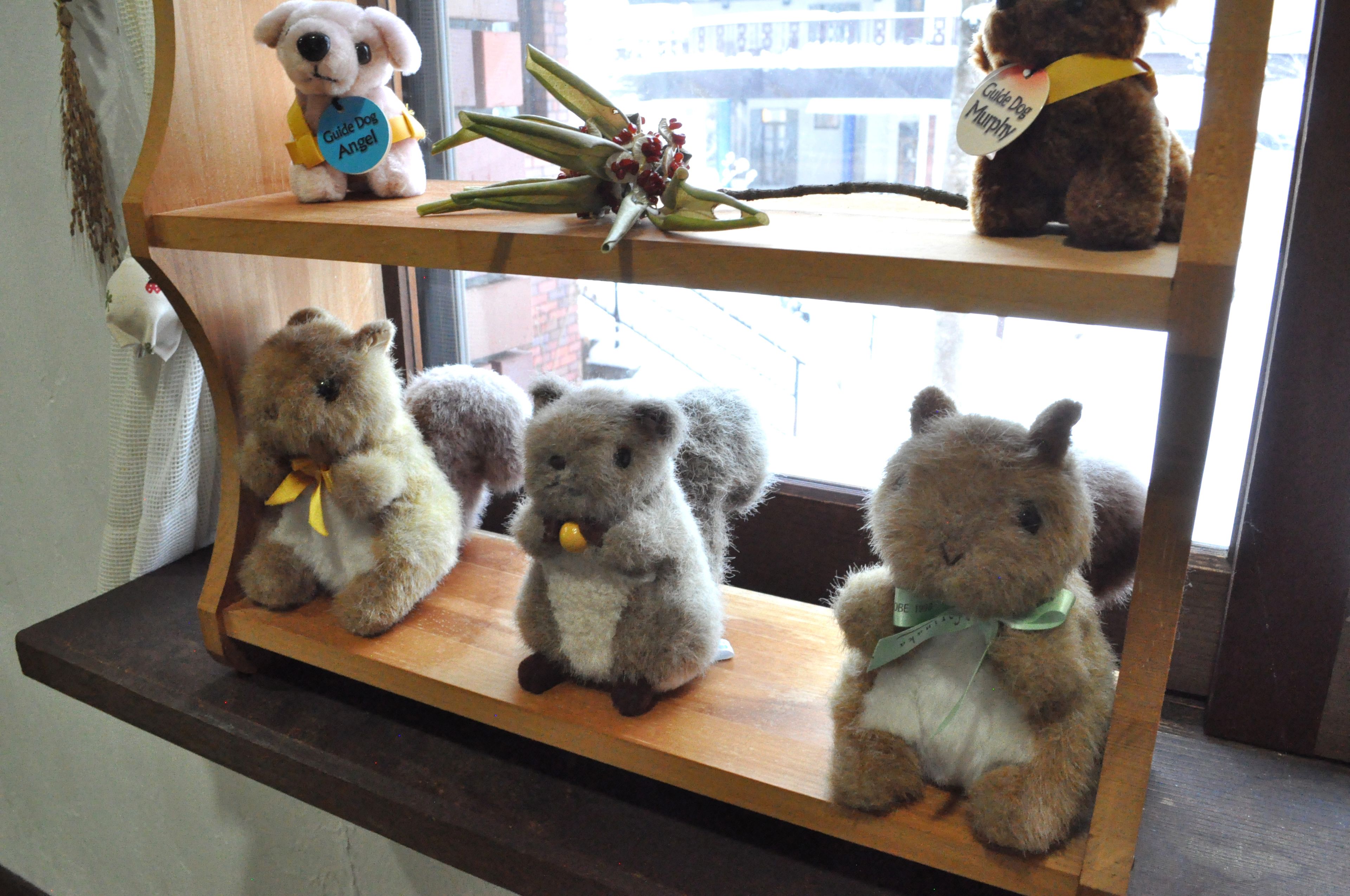 A shelf with four plush toys and a bouquet of flowers.