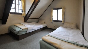 A room with two beds, a sloped ceiling, and windows with curtains.