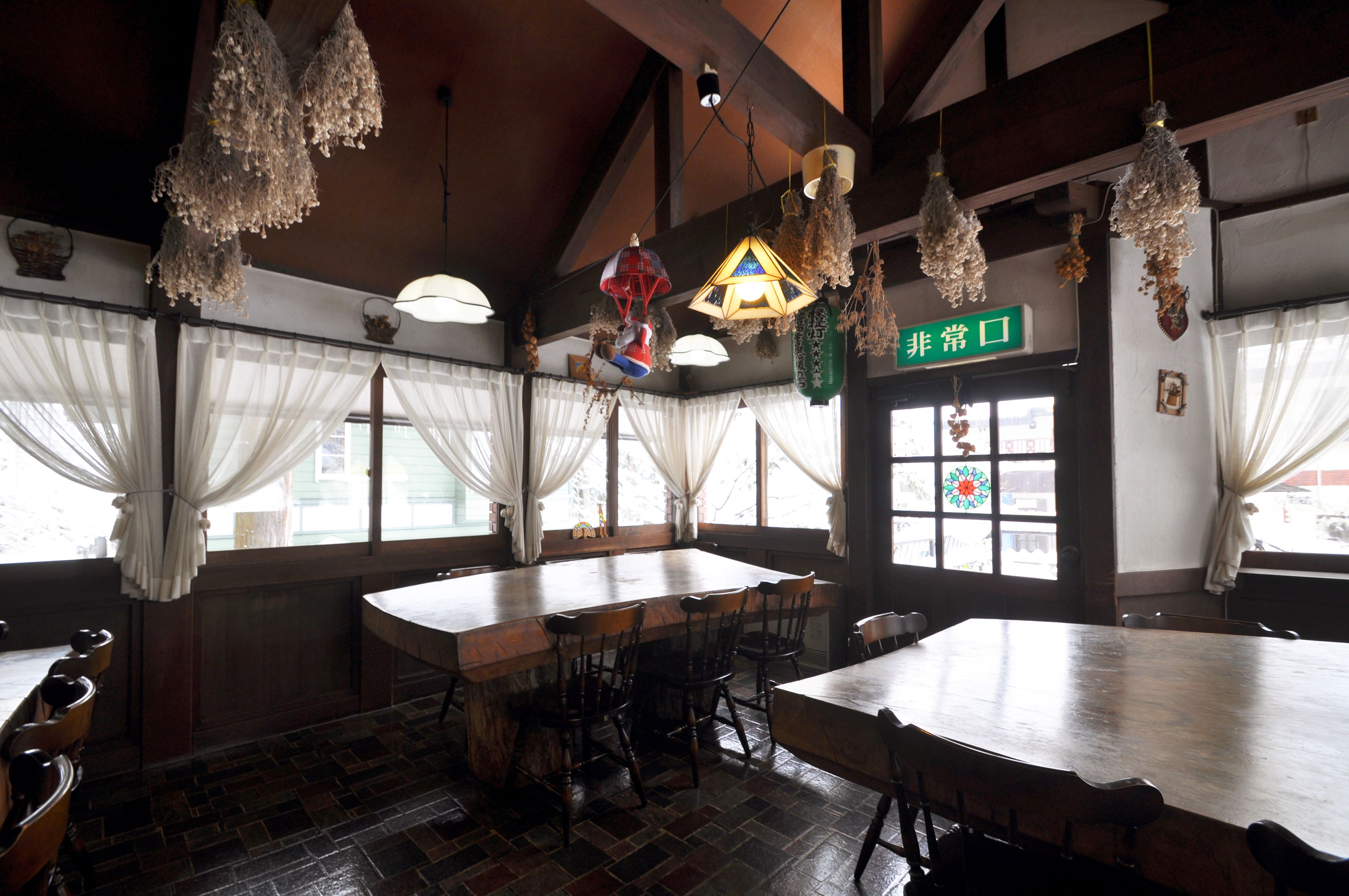 A traditional Japanese restaurant with a large wooden table, multiple chairs, and hanging lanterns.