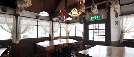 A traditional Japanese restaurant with a large wooden table, multiple chairs, and hanging lanterns.
