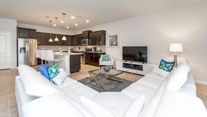 A modern living room with a white sofa, a coffee table, and a TV.