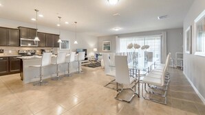 A modern kitchen with dark cabinets, a central island, and pendant lighting.