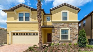 A two-story house with a garage, stone facade, and a palm tree in the front yard.