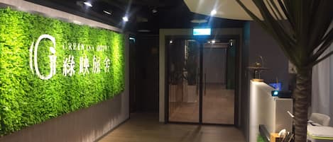 A reception area with a green wall, a wooden floor, and a palm tree.