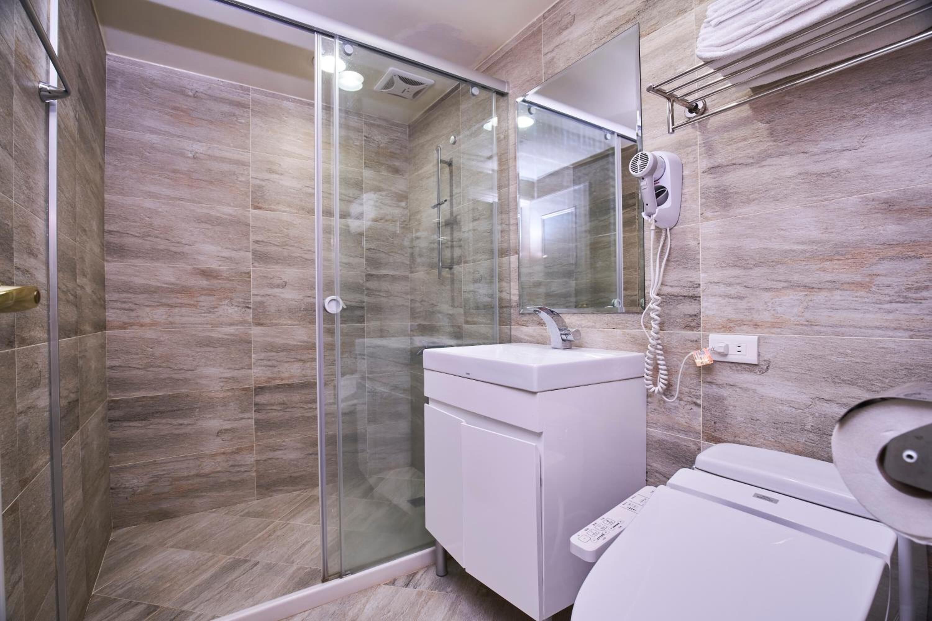 A modern bathroom with a glass-enclosed shower, a white sink, and a toilet.