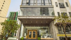 Un hotel moderno con una entrada destacada, varios pisos y un letrero visible que dice "JOLIA HOTEL".