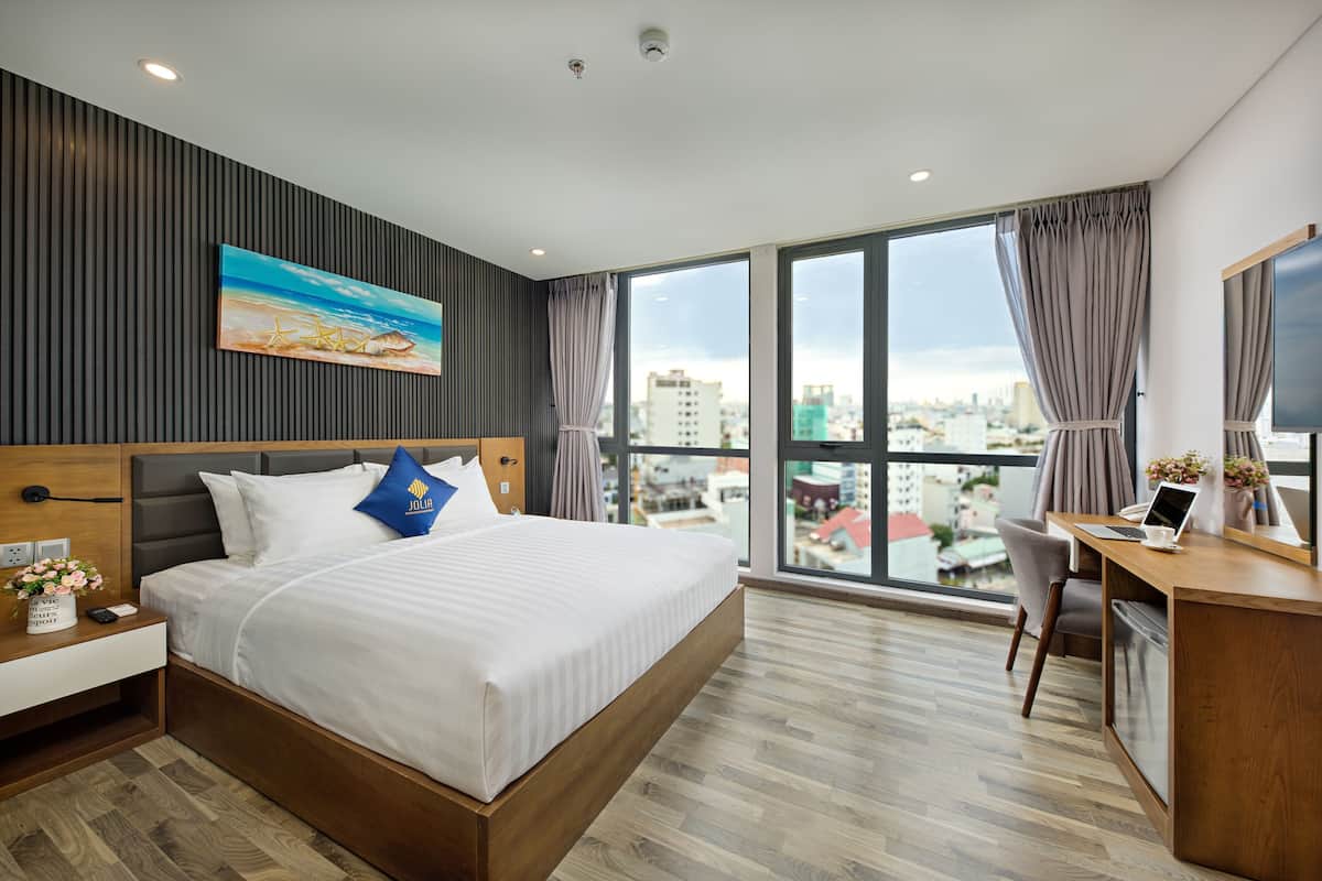 Una habitación de hotel moderna con una cama grande, un escritorio y vistas a la ciudad.