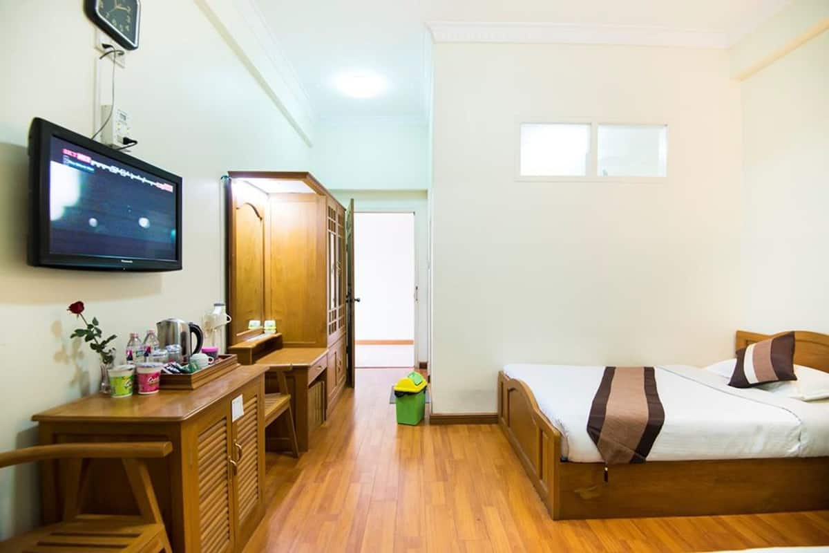 A compact room with a bed, a desk, a television, and a wardrobe.
