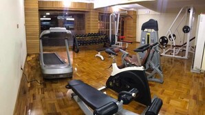 Un gimnasio con cinta de correr, elíptica, banco de pesas y diversas máquinas de ejercicio.