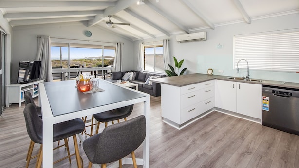 A modern kitchen with a dining area, large windows, and a view of the landscape. - Sunset View- Magnificiant Ocean Views (Lancelin)
