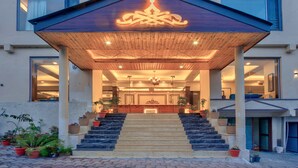 A hotel entrance with a wooden canopy, a reception desk, and a staircase leading to the lobby. - The Katoch Grand Resort (Manali)