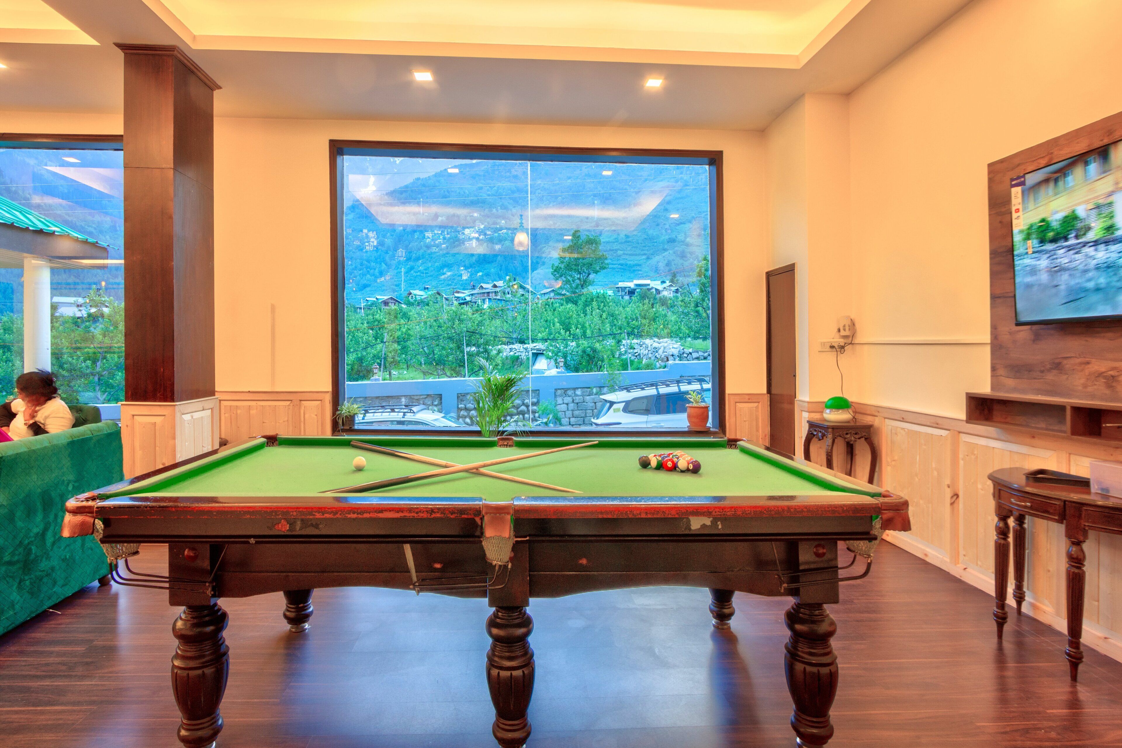 A pool table with a clear view of a mountainous landscape through large windows.