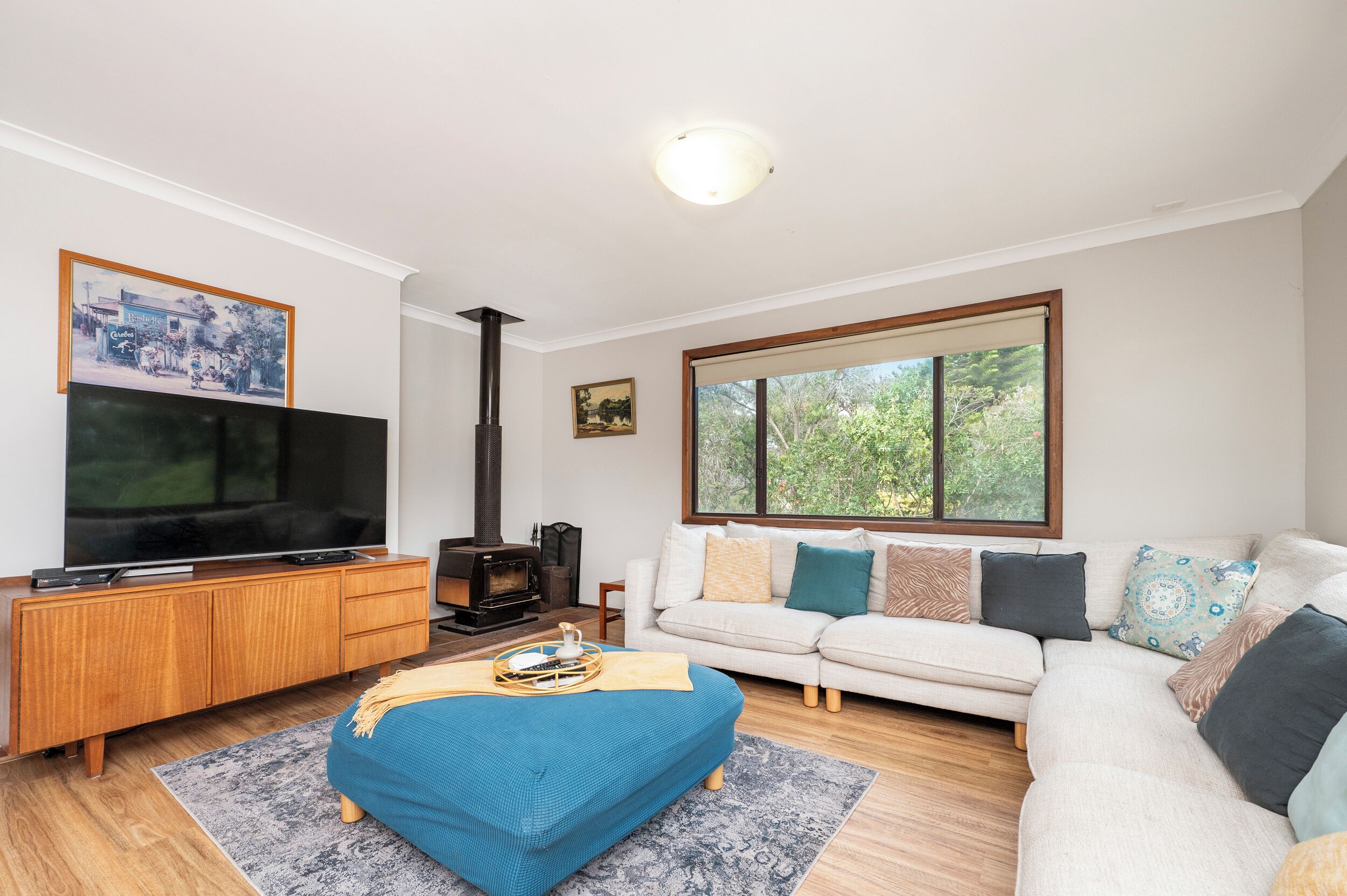 A living room with a TV, fireplace, sofa, and large windows.