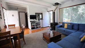 Un salon avec un canapé bleu, une table basse en bois, un téléviseur posé sur un meuble et une cheminée.