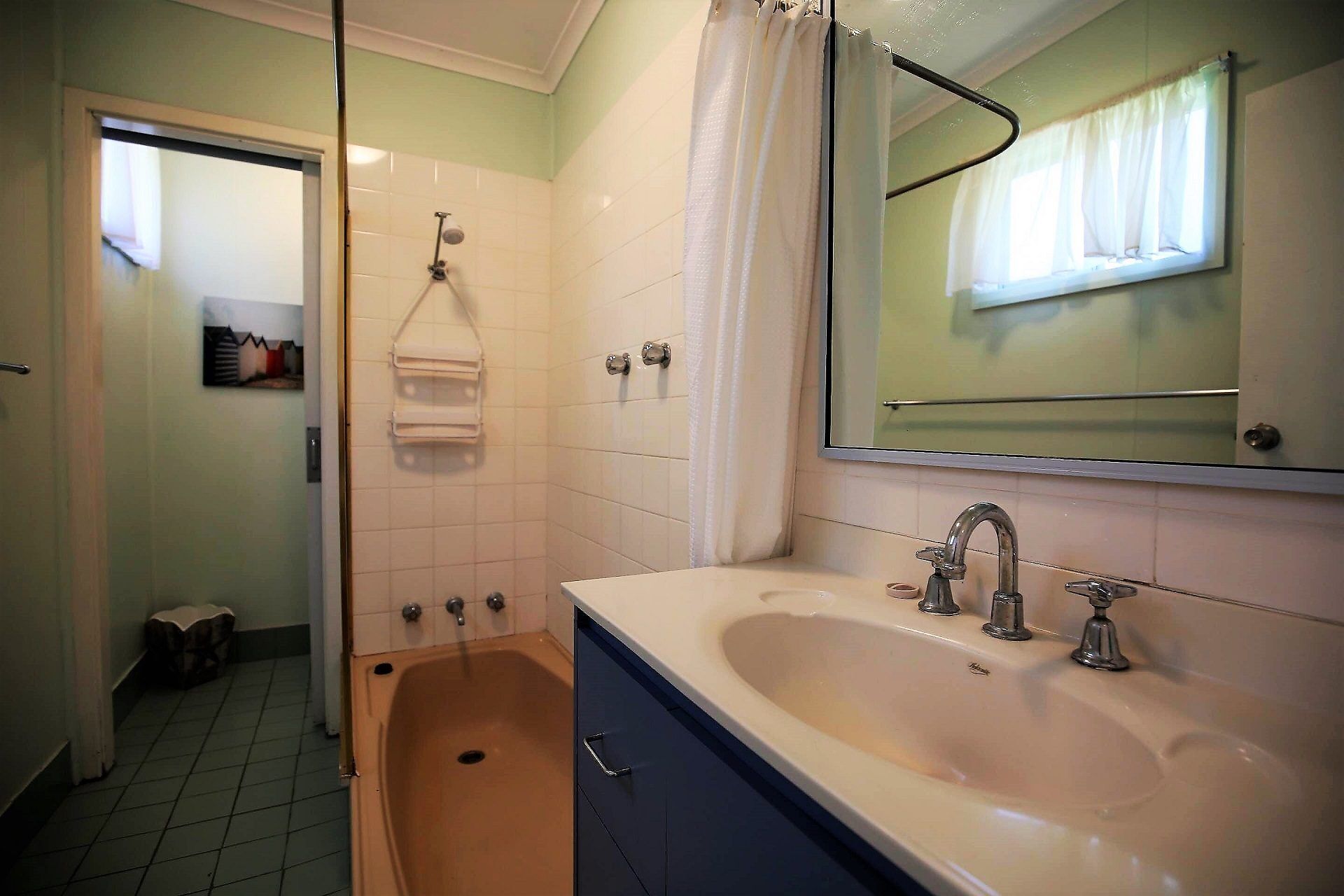Un baño con bañera, lavamanos, espejo y toallero.