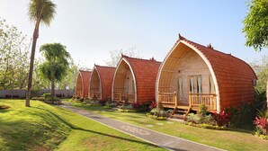 Una hilera de cabañas de madera con techos abovedados y balcones de madera, rodeadas de jardines cuidados y un sendero despejado.