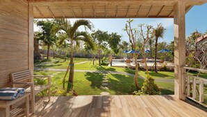 A wooden deck with a view of a pool area, including lounge chairs and umbrellas. - Bukal Sari Villas Uluwatu (Pecatu)