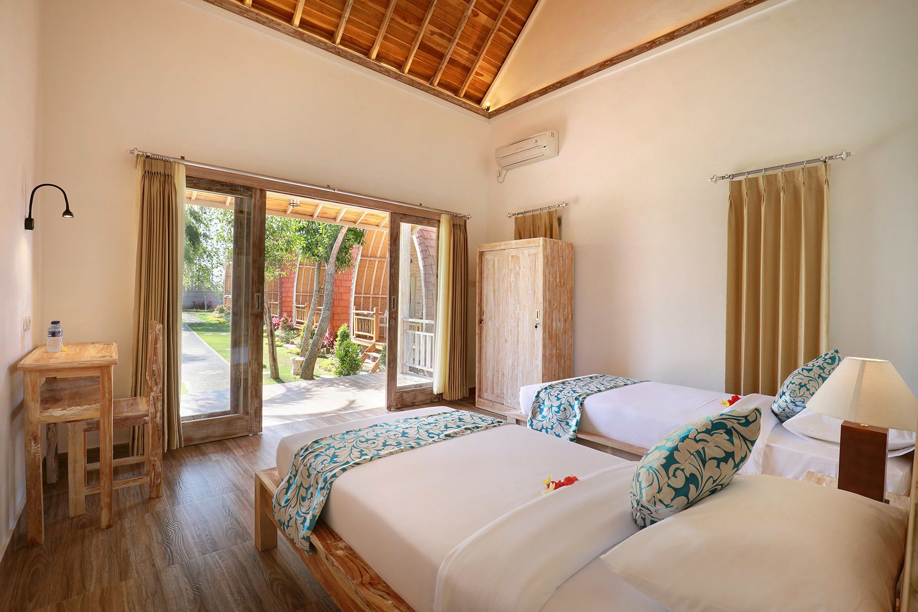 Un dormitorio con dos camas, un armario de madera, una mesita y una ventana con cortinas.