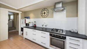 A modern kitchen with white cabinets, a black countertop, a stainless steel stove, and a built-in oven. - Blueshack - Walking distance to foreshore (Guilderton)