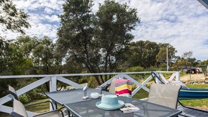 An outdoor patio with a table and chairs, a striped towel, and a hat on the table. - Blueshack - Walking distance to foreshore (Guilderton)