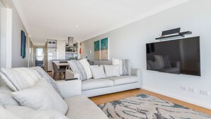 Ett modernt vardagsrum med en soffa, en TV som är monterad på väggen och en matplats i bakgrunden.