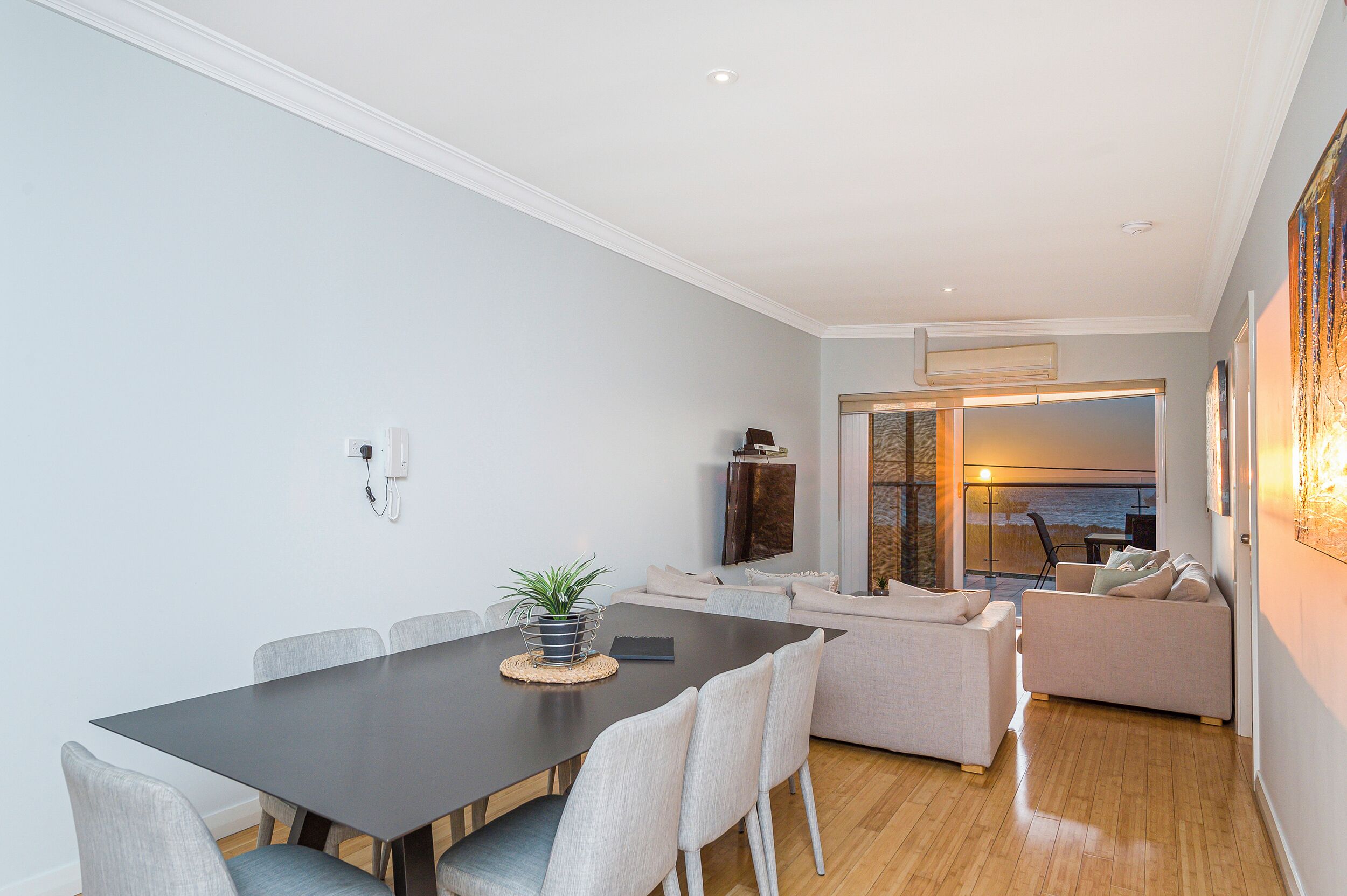 A modern living room with a dining area, a sofa, and a view of the outdoors.