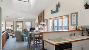 Amplia sala de estar con cocina, mesa de comedor y vista al océano.