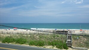 Una playa con un paseo de madera que conduce a la orilla, arena y el océano.