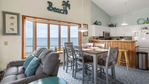 Un comedor con vista al océano, una cocina con armarios blancos y un cartel que dice 'Beach'.