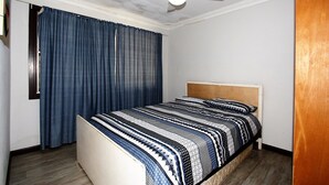 A bedroom with a bed, a ceiling fan, and a window with curtains.