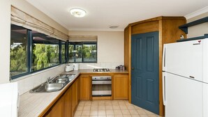 Una cucina compatta con lavandino, fornelli, forno e una porta blu.
