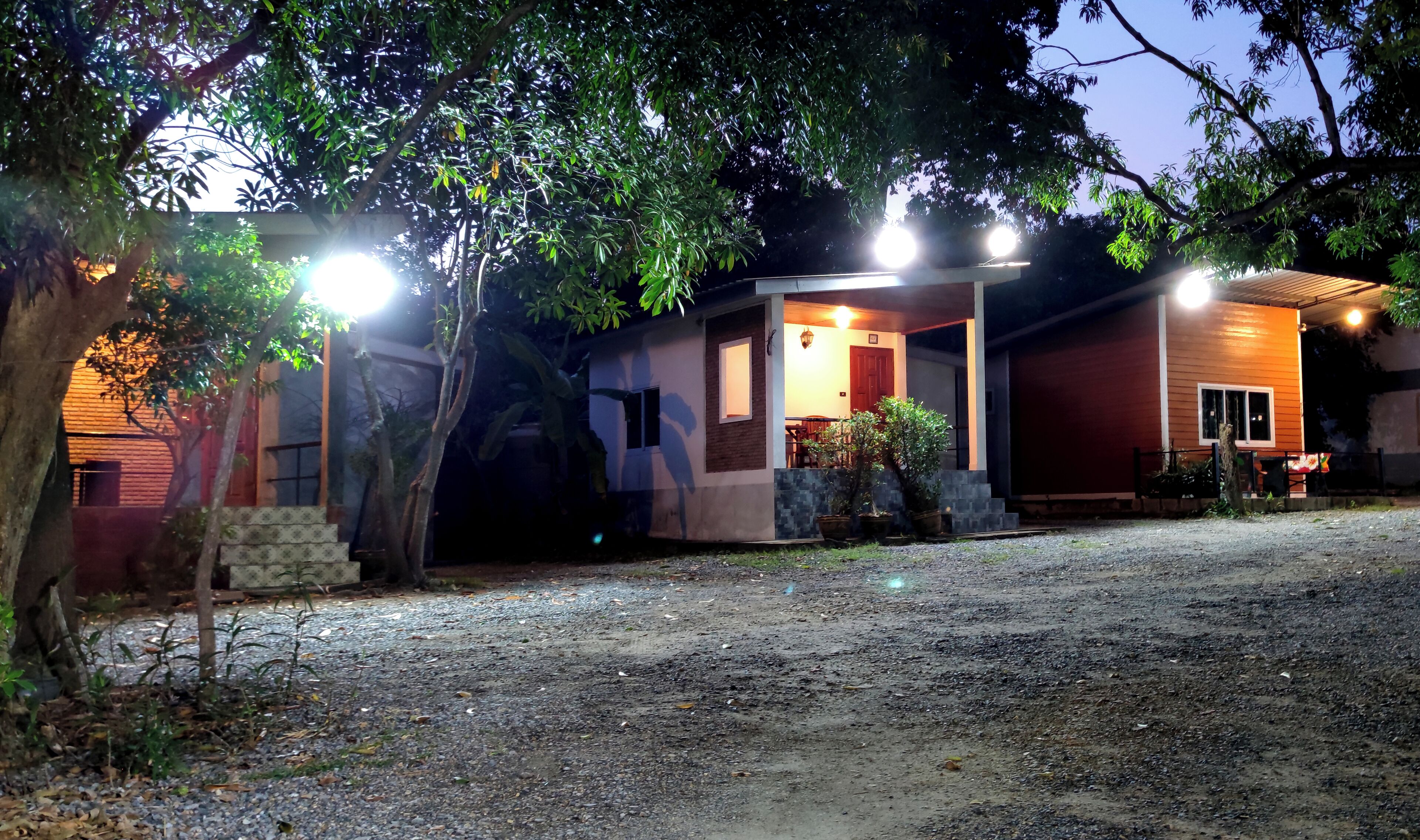 A two-story house with a porch, a small garden, and a gravel driveway.