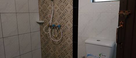 Un baño con inodoro, ducha y pared de azulejos con diseño geométrico.