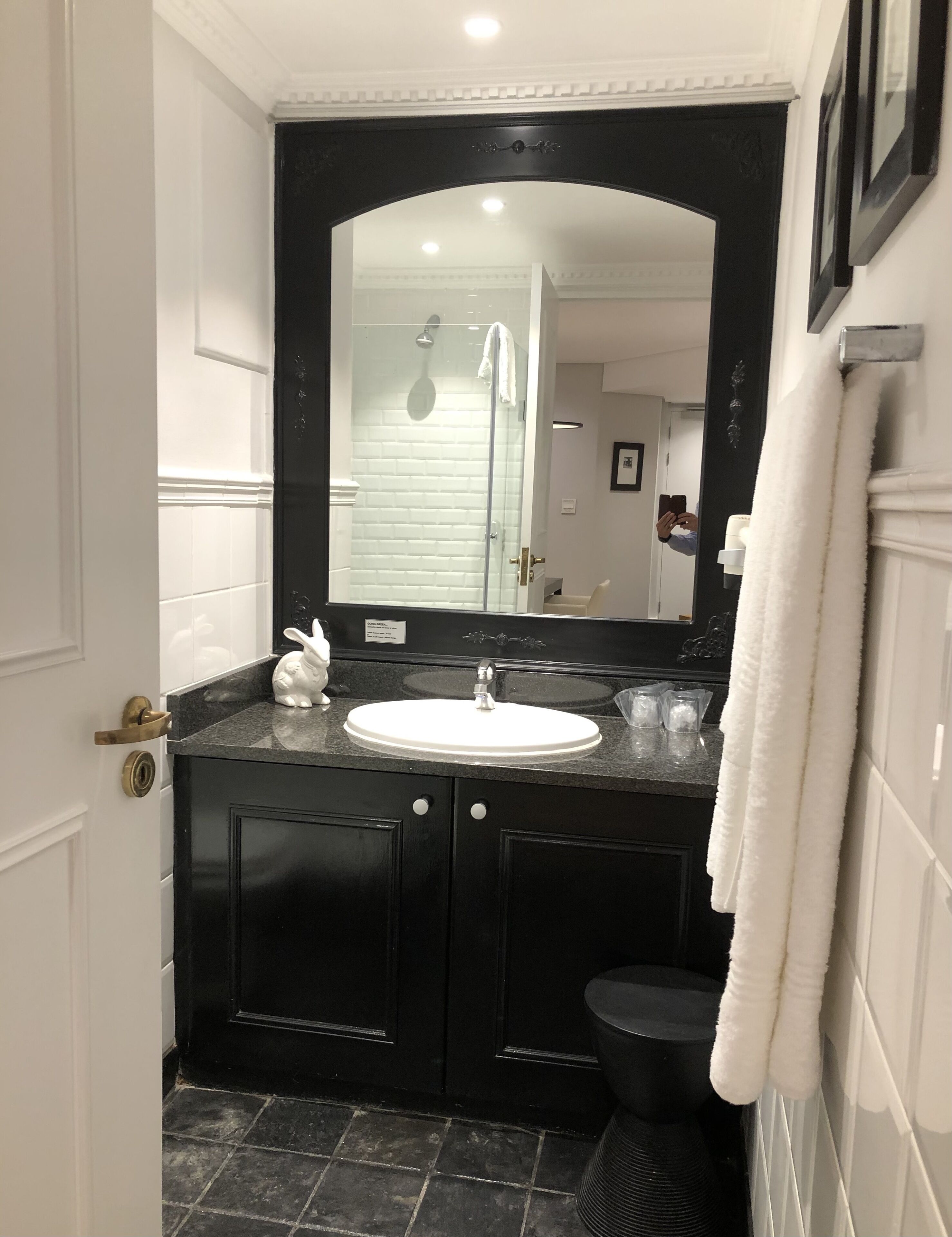 A bathroom with a white sink, black vanity, and a large mirror.