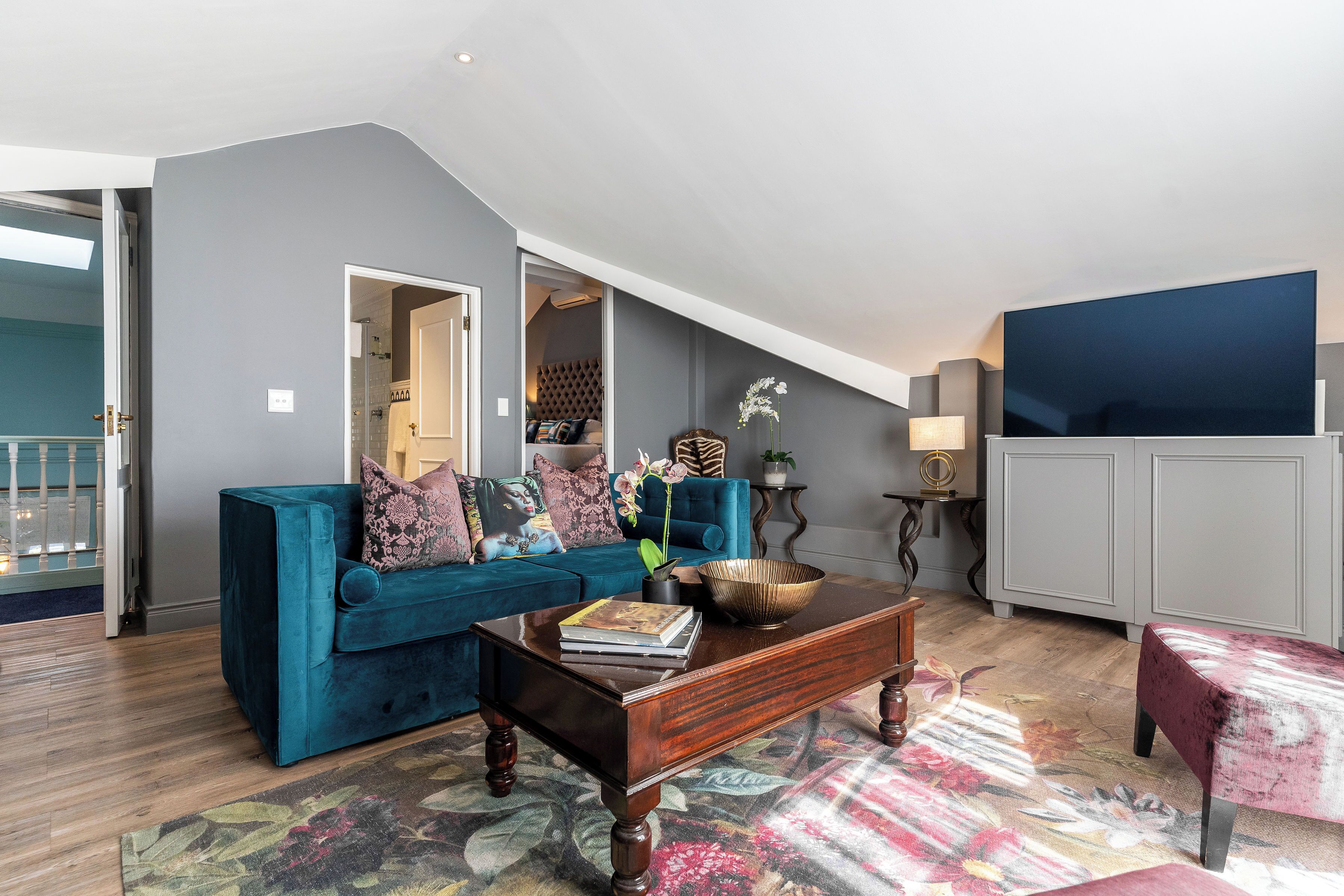 Un salon moderne avec un canapé bleu, une table basse en bois et un grand téléviseur.