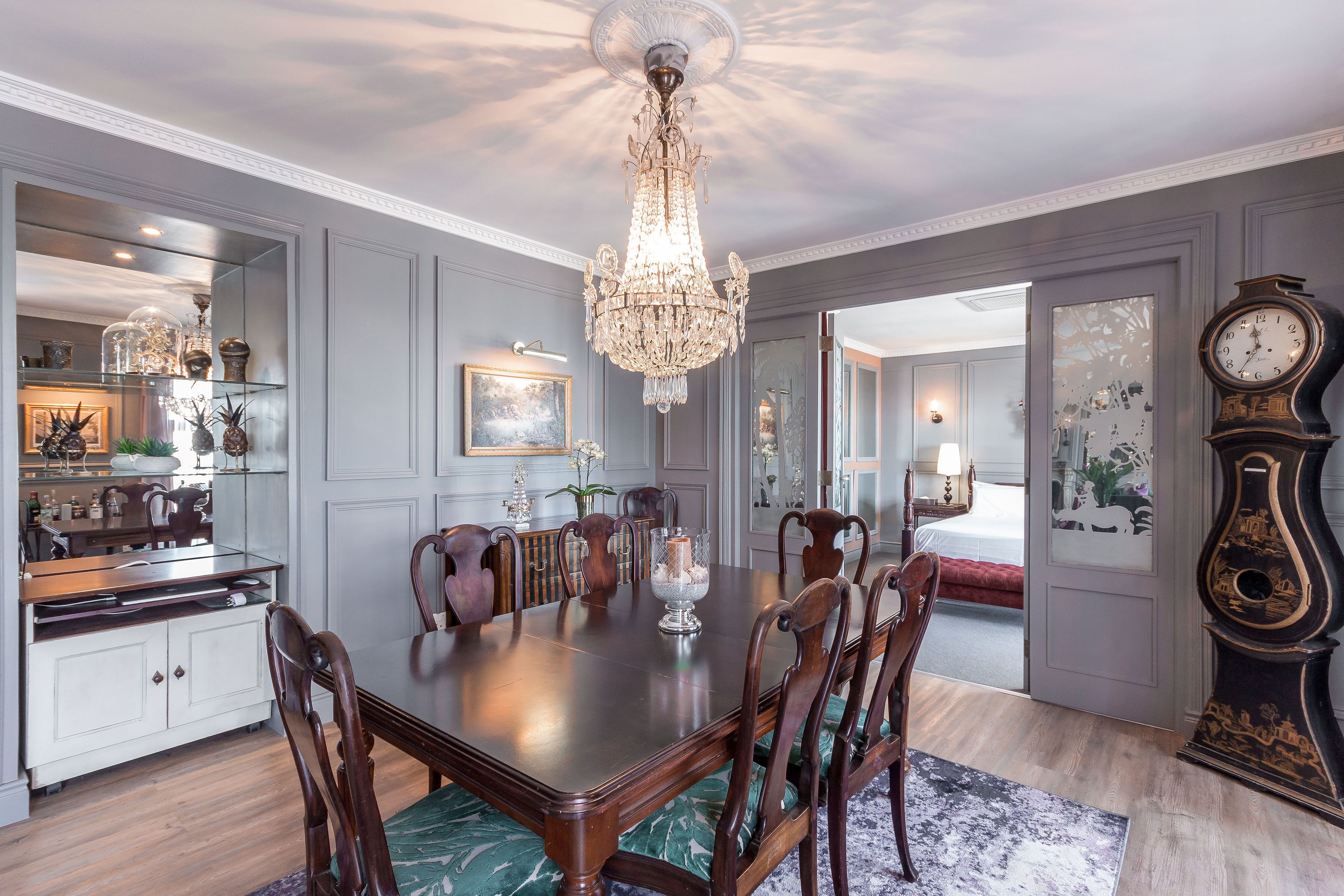 Een stijlvolle eetkamer met een kroonluchter, een houten eettafel en stoelen.