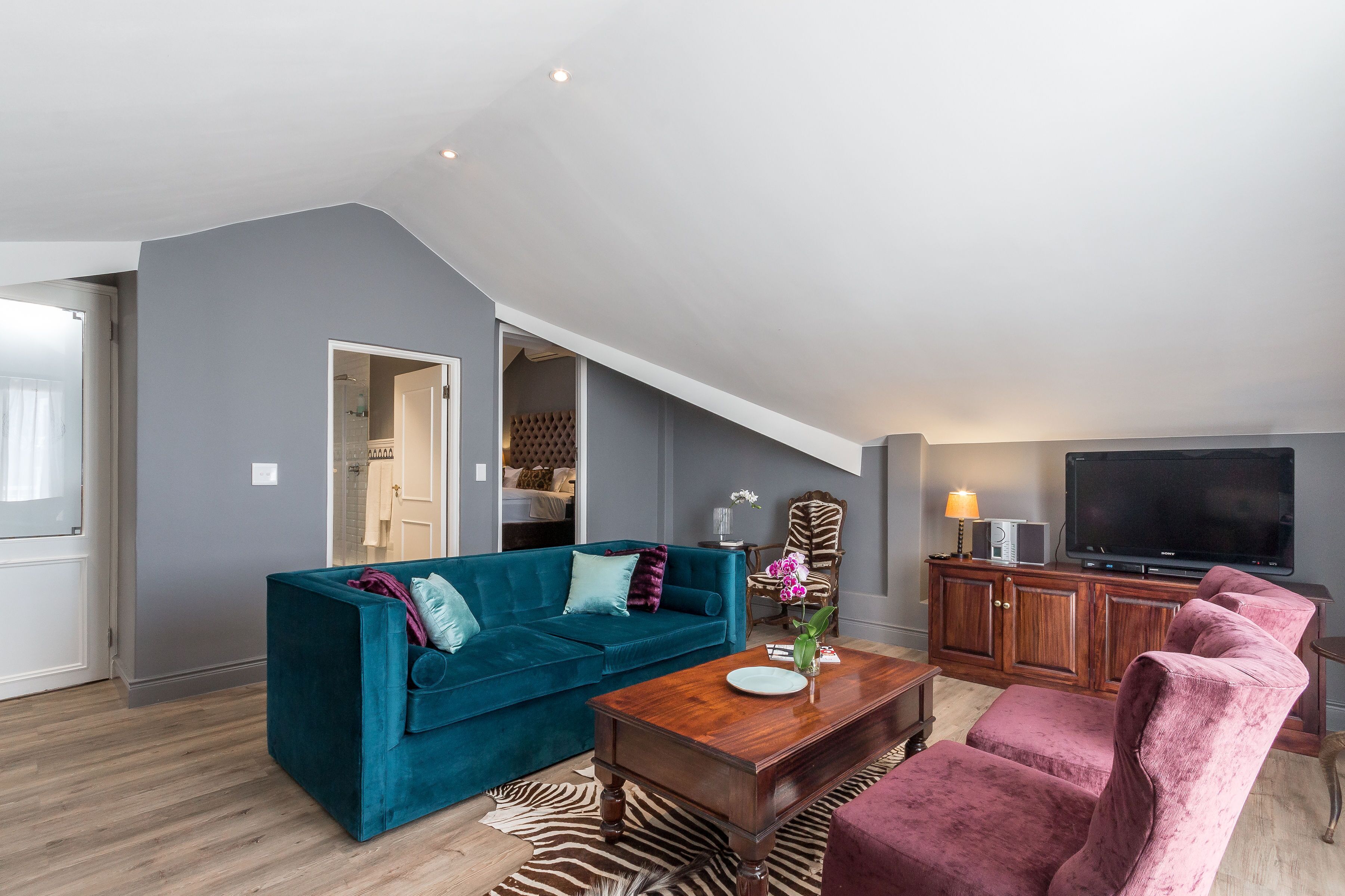 Ein modernes Wohnzimmer mit einem blauen Sofa, einem Holztisch und einem rosa Sessel.
