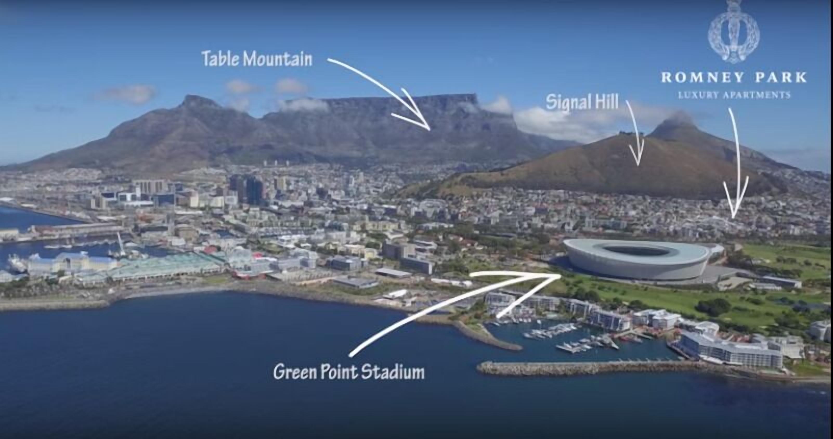 Vue aérienne d’une ville côtière, avec des monuments emblématiques tels que la montagne de la Table, Signal Hill et le stade de Green Point.