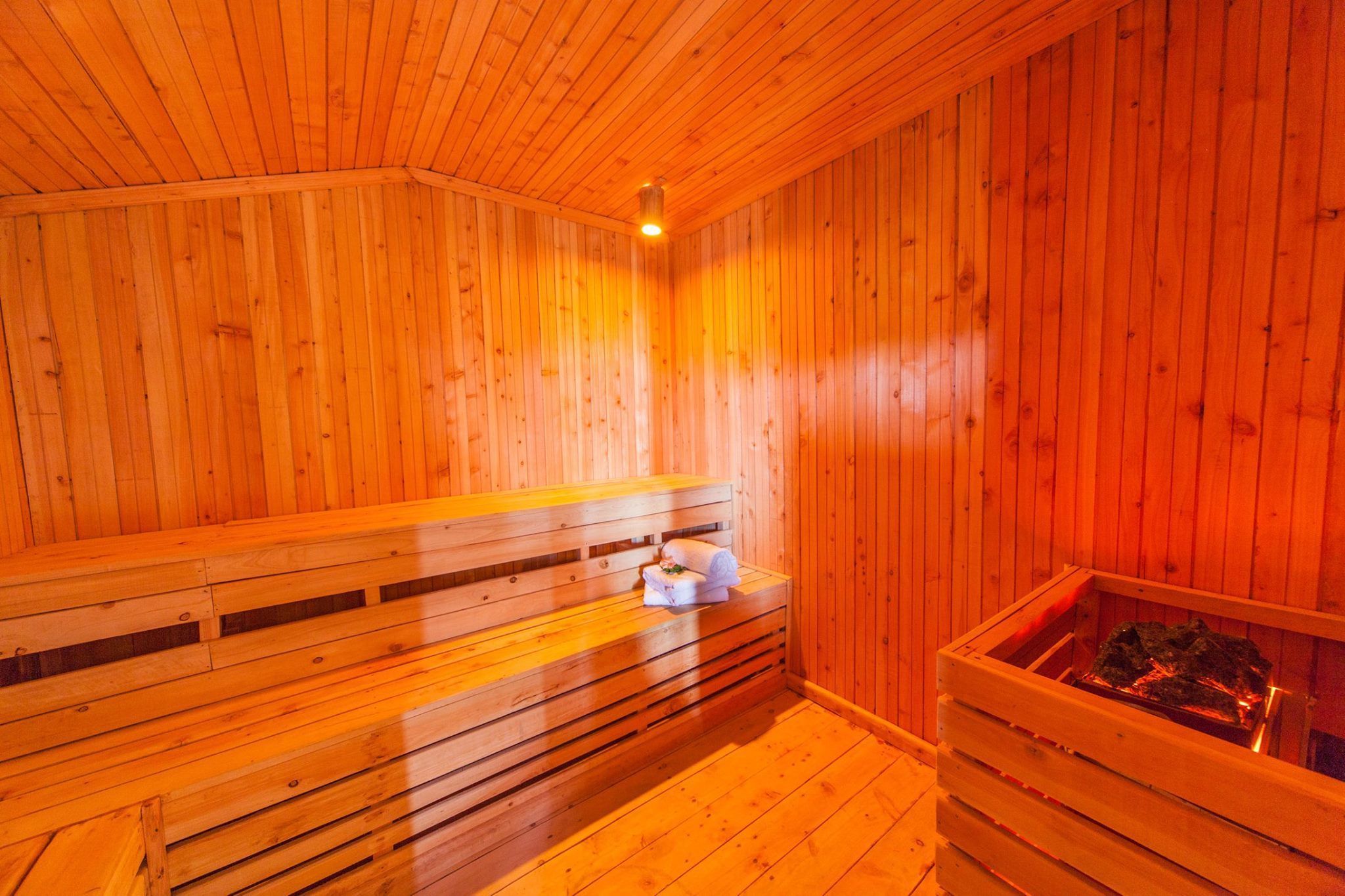 Un sauna en bois avec des bancs et un bain de pierres chauffées.