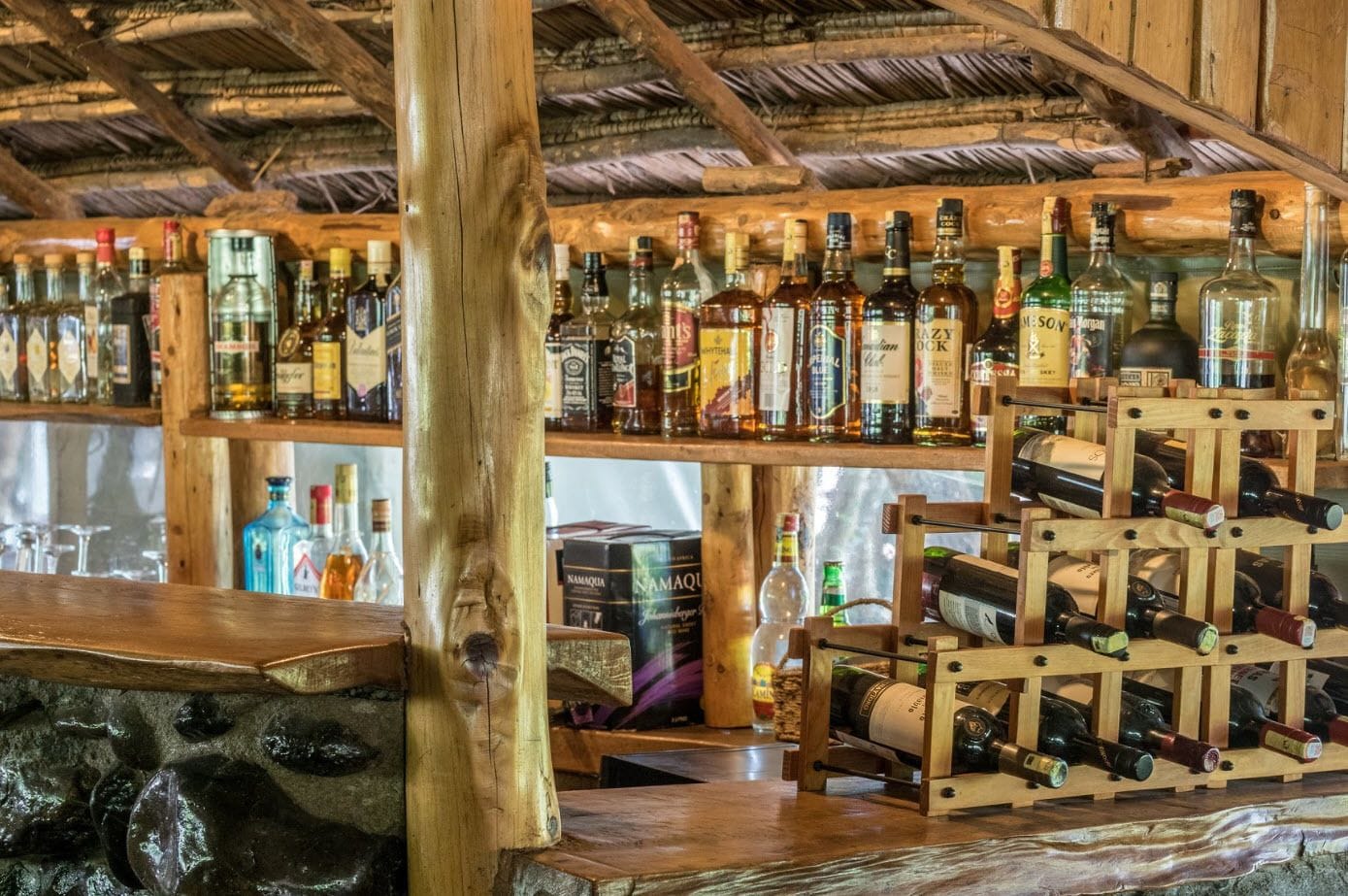 A bar area with wooden shelves and racks holding various bottles of alcohol.