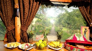 A breakfast table with plates of food, a bowl of fruit, and a basket of bread. - Rhino Watch safari Lodge (Nyahururu)