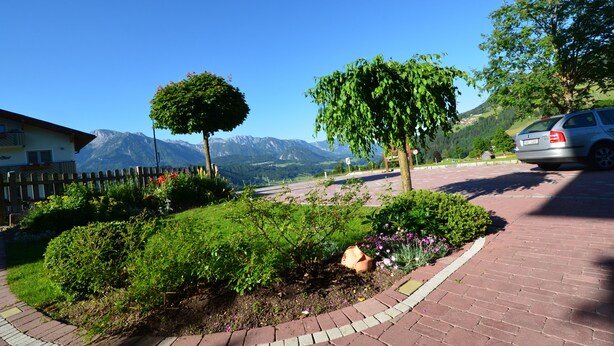 Une allée pavée mène à un bâtiment dont l’arrière-plan est constitué d’une chaîne de montagnes.