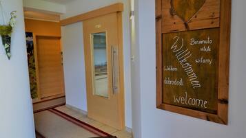 Un pasillo con un letrero de madera que dice 'Bienvenido', una puerta y una alfombra roja que conduce a una habitación.