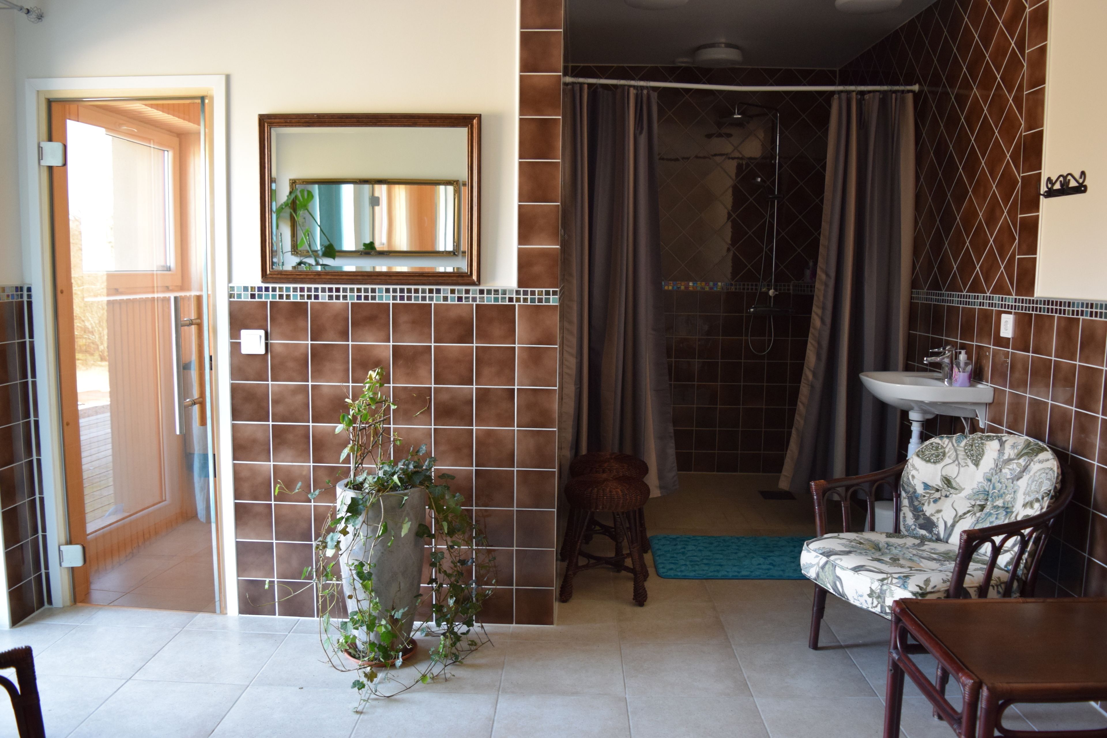 A bathroom with a shower, a sink, and a chair.