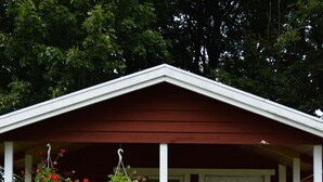 Un petit bâtiment d’un seul étage, avec une porte blanche et un porche.