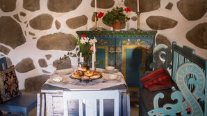 Un coin repas avec une table dressée pour le repas, un meuble décoratif et un mur en pierre en arrière-plan.