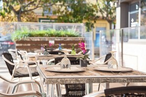 An outdoor dining area with tables set for two, featuring metal chairs and a glass table. - Hotel Palau de girona (Sant Julia de Ramis)