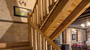 A wooden staircase with a handrail, leading to a dining area with tables and chairs.