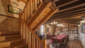 A wooden staircase leading to a dining area with a tiled floor and wooden furniture.