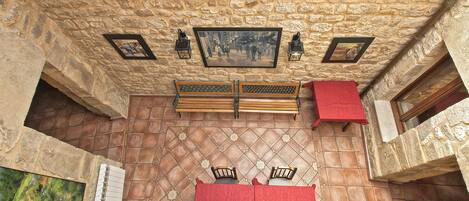 A room with a stone wall, wooden benches, a red tablecloth, and a framed picture on the wall.